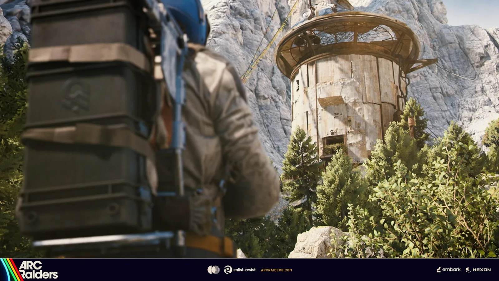 A Raider looking up at an Outpost tower in the mountains